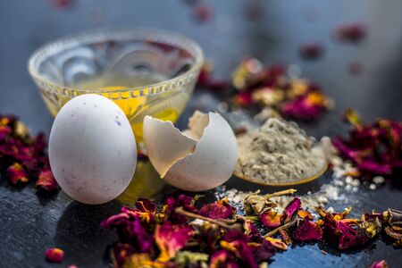 Egg and besan or chickpea flour or gram flour on wooden surface in a glass bowl along with raw egg...