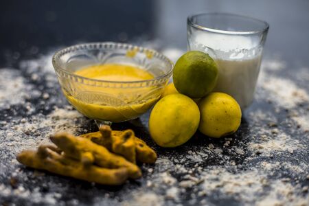 Lemon face mask on the wooden surface consisting lemon juice, gram flour or chickpea flour, turmeric...