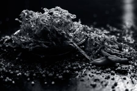 Famous Indian and Gujarati snack dish in a transparent glass plate isolated on the wooden surface i.e. Potato and sago ball chakli or aloo and sabudana ni chakili. uncooked or raw dried.の写真素材
