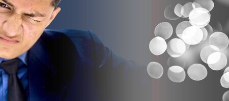 Portrait shot of a too young businessman wearing a blue colored suit and black colored necktie and making or expressing doubtfulness on his face.の写真素材