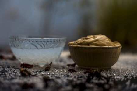 Ubtan/face mask/face pack of Multani mitti or fuller's earth on wooden surface in a glass bowl consisting of Multani mitti and coconut oil for the remedy or treatment of suntan.On the wooden surface.の写真素材