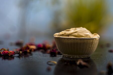 Ubtan/face mask/face pack of Multani mitti or fuller's earth on wooden surface in a glass bowl consisting of Multani mitti and rose water for the remedy or treatment of oily skin.On wooden surface.の写真素材