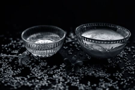 A famous natural method for dandruff on wooden surface in a glass bowl consisting of fenugreek seeds powder well-mixed with curd in a glass bowl.Along with raw curd and fenugreek seeds on the surface.の写真素材