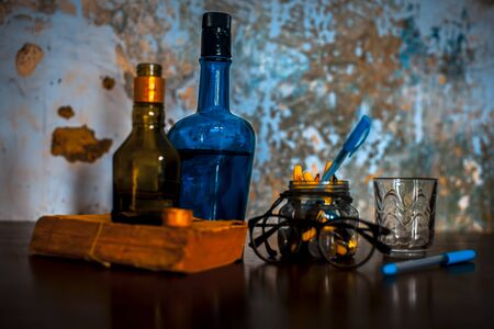 Traditional set alcohol bottle with glasses on a wooden table along with a book and some pens.Traditional Still life.Still life concept in dark gothic colors.の写真素材
