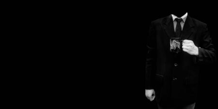 An unrecognizable office employee wearing a blue colored suit and posing with a cup of coffee in his hands isolated on a black colored background.の写真素材