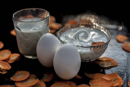Carrot face mask on black wooden surface in a glass bowl consisting of some egg white, carrot juice, yogurt, and milk.Used to get softer brighter skin. Horizontal shot.の写真素材