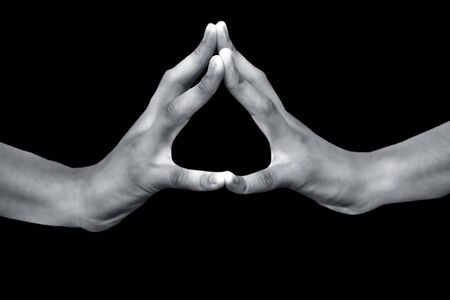 Close up shot of male hands demonstrating and meditating with Hakini Yoga Mudra isolated on a black colored background, Horizontal shot.の写真素材