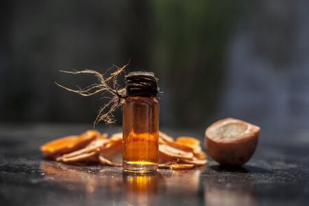Fresh sliced cut carrots on a black table surface with blurred background and some extracted essential oil in a small transparent glass bottle. Horizontal shot.の写真素材