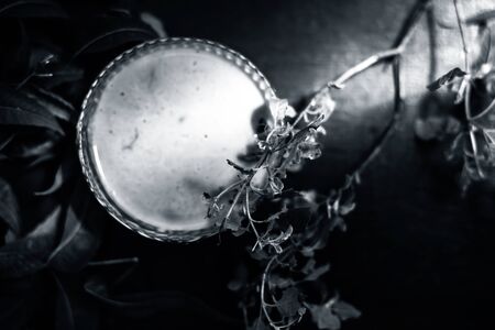 Close up shot of glass bowl full of tulsi or basil and neem or Indian lilac paste in it along with fresh neem and tulsi leaves on a brown wooden surface.の写真素材