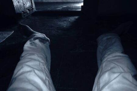 Self-shot of male legs wearing white-colored denim jeans and white shoes. Long legs. Black and white...
