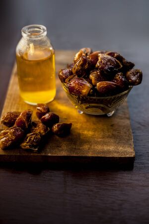 Dates syrup in a glass along with some raw dried dates and some cooking oil in a glass bottle on a...