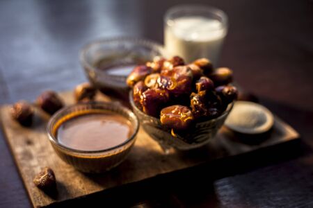 Dates face mask on a brown wooden surface with some golden light and selective focus consisting of some dates, milk, semolina, and honey. For softer and brighter skin. Horizontal shot.の写真素材