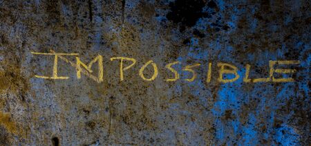 Creative and unique Possible written on a rough wall. Shot of impossible word written with a cross...