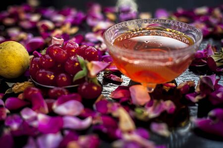 Face mask for pimple and acne treatment on a black colored board consisting of some mashed sweet cherries, lemon juice, and honey. Shot of fresh cherries, lemons and some honey along with rose petals.の写真素材
