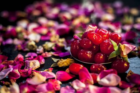 Skin brightening DIY face mask on a black wooden board consisting of some sweet cherries well mixed with yogurt. Shot of fresh sweet cherries along with some yogurt and rose petals.の写真素材