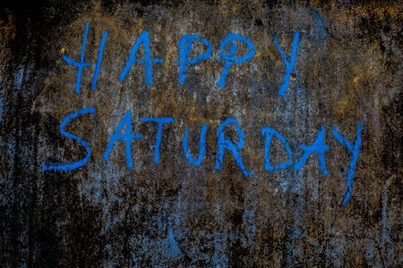 Happy Saturday wrote on the rough wall with blue colored chalk, close up horizontal shot.の写真素材