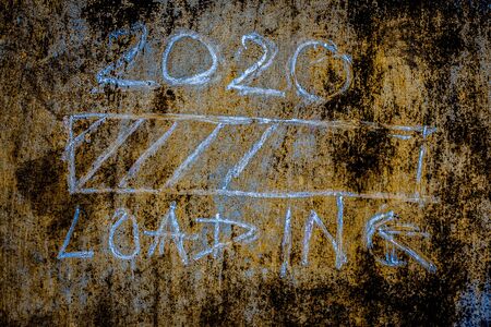 Creative 2020 loading sign on the rough brownish wall. Close up shot.