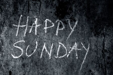 Happy Sunday wrote on the rough wall with yellow-colored chalk, close up horizontal shot.の写真素材