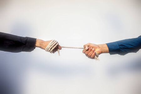 Close up shot of two male hand playing tug of war over blurred background.の写真素材