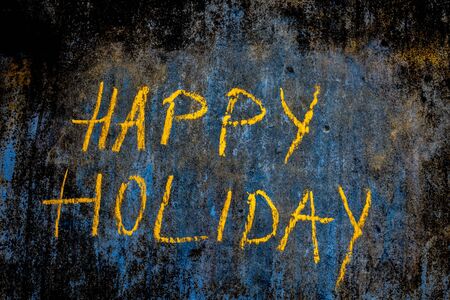 Happy Holiday wrote on the rough wall with yellow chalk, close up horizontal shot.の写真素材