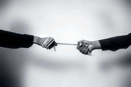 Close up shot of two male hand playing tug of war over blurred background.の写真素材
