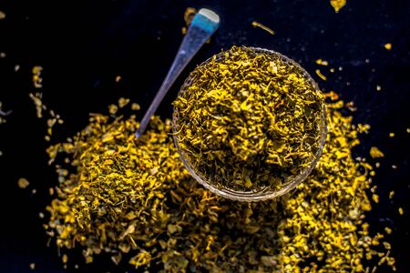 Close up short of popular Indian Spice Kasuri Methi (Dried Fenugreek Leaves) in a bowl and some on a spoon on a black colored glossy surface.の写真素材