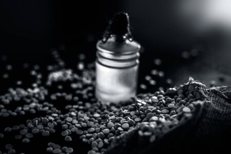 Close up of refined chickpea oil in a glass bottle on a glossy black wooden surface with raw yellow lentil with it.の写真素材