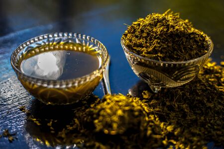 Shot of raw dried Kasuri methi along with its freshly prepared paste in a glass bowl on a black shiny surface.の写真素材