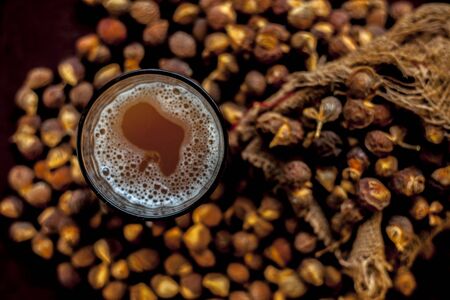 Close up shot of fresh raw soapnut on brown surface along with its solution or liquid in a glass alongside it.の写真素材