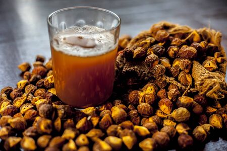 Close up shot of fresh raw soapnut on brown surface along with its solution or liquid in a glass alongside it.の写真素材