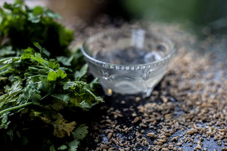 Exfoliating skincare face mask on a black colored surface consisting of some coriander leaves and...