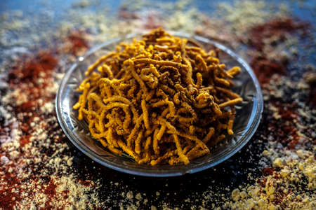 Diwali and Shravan Som special Teekha Gathiya in a glass plate along with some spread chickpea flour, red chili powder, and other ingredients that are needed to make the snack on a black surface.の写真素材
