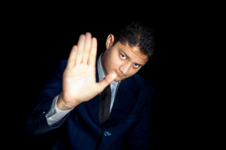 A tired man saying NO TO WORK isolated on a black colored background wearing a blue colored suit.の写真素材