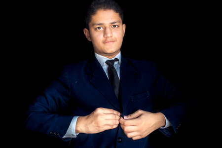 Portrait shot of a businessman adjusting his tie before a meeting isolated on black background.の写真素材