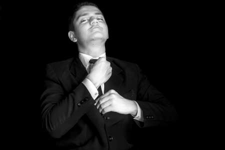 Portrait shot of a businessman adjusting his tie before a meeting isolated on black background.の写真素材