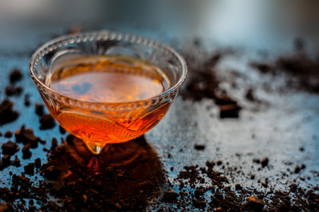 A bowl full of chocolate milk on a black wooden surface with some raw cocoa powder sprinkled around...
