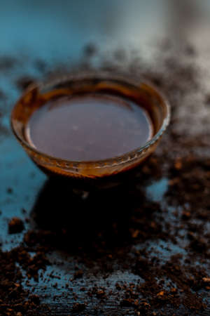 A bowl full of chocolate milk on a black wooden surface with some raw cocoa powder sprinkled around it.の写真素材