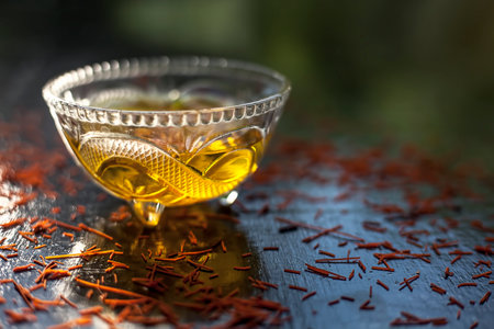 Saffron soaked in a glass bowl on a black surface with some raw saffron/Kesar threads with it.の写真素材
