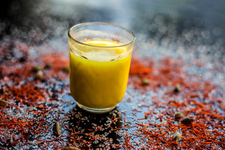 Close up shot of red amaranth leaves along with their extracted oil in a glass bottle with it on a black glossy surface.の写真素材