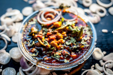 Slightly high angle shot of a glass plate full of Chole bhature in it on a black background along...