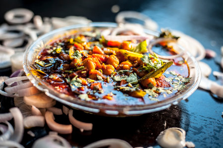 Slightly high angle shot of a glass plate full of Chole bhature in it on a black background along with some phudina/mint chutney and onion rings with it.の写真素材
