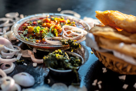 Full breakfast plate on the black surface. Indian Delhi style Chole bhature along with some onion rings and pudhina/mint chutney on a black surface.の写真素材