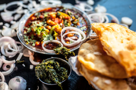 Full breakfast plate on the black surface. Indian Delhi style Chole bhature along with some onion rings and pudhina/mint chutney on a black surface.の写真素材