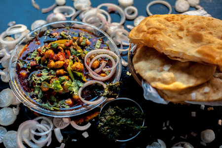Full breakfast plate on the black surface. Indian Delhi style Chole bhature along with some onion...