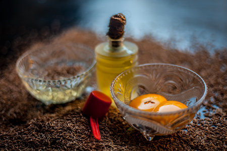 Hair mask for healthy long hair consisting of cumin seeds or zeera or jeera along with some raw egg yolk, water and some olive oil on a brown colored wooden surface.の写真素材