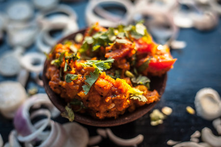 Close up shot of sukhi bhaji or jeera aloo in a clay bowl along with some cut onion rings.