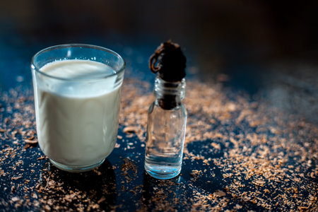 Glycerine skin cleanser on a black surface. Shot of glycerine in a glass bottle along with a glass...
