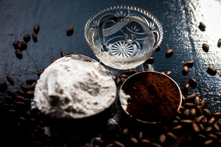 Coffee face mask for skin whitening on a black shiny wooden surface consisting of some coffee powder, lukewarm water, and rice flour.の写真素材
