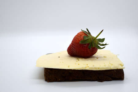 Strawberry on a slice of chocolate cake on a white background