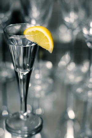 Glass of tequiilla with yellow lemon on mirrored backgroundの写真素材